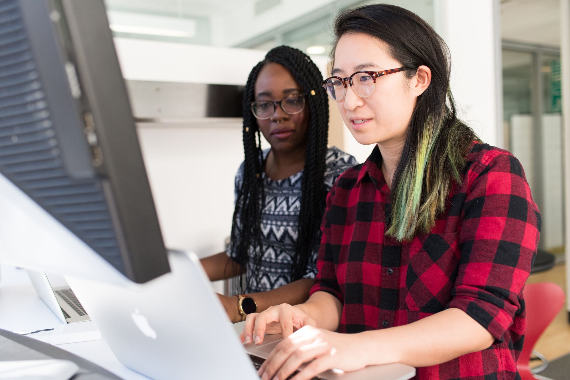 developers sitting at desk, looking at computer and working together