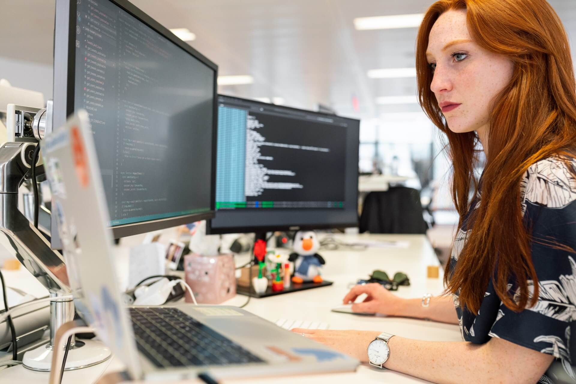 developer working at a desk with laptop and two extra screens