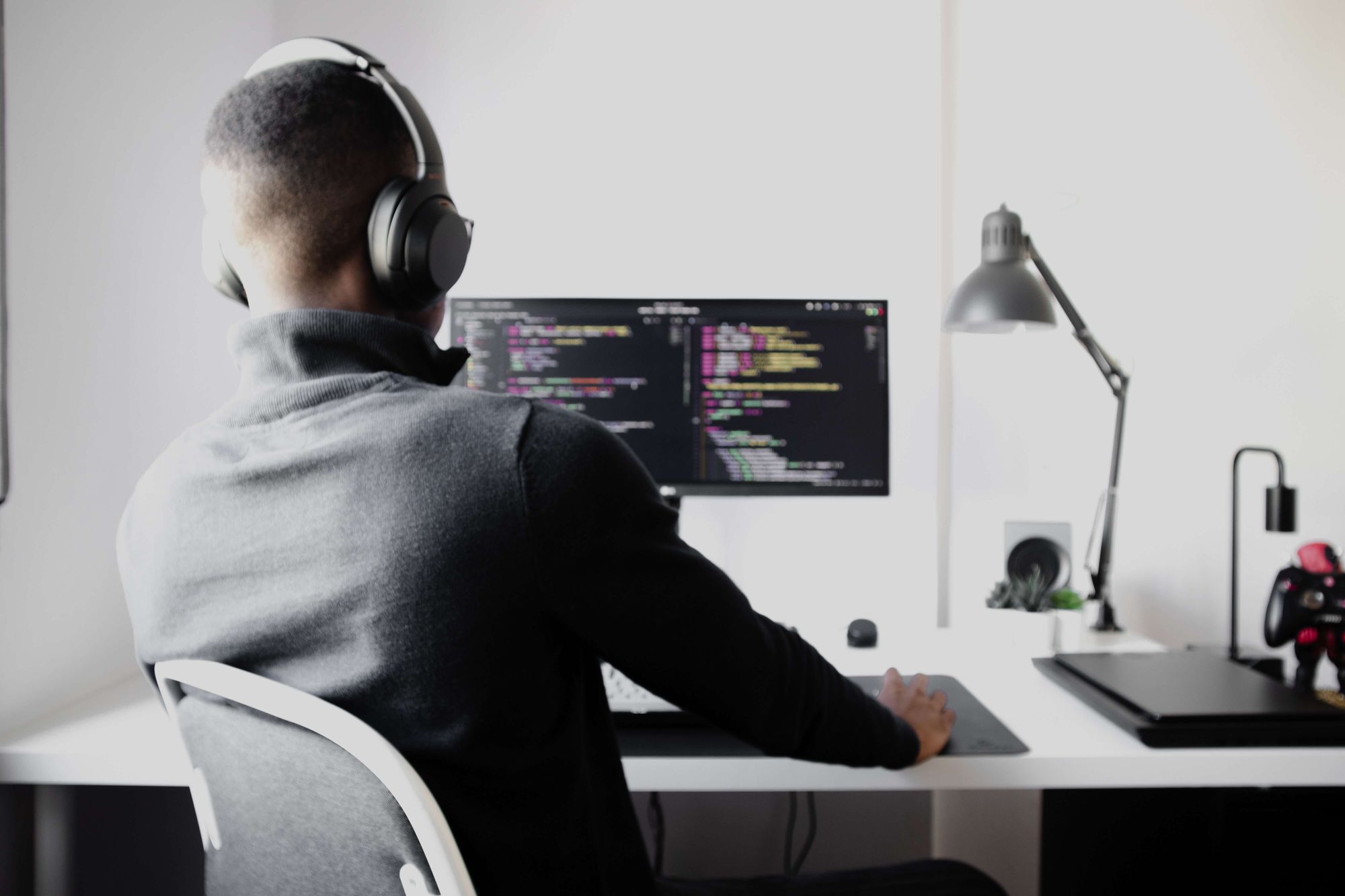 developer sitting at a desk on his computer with code on the screen